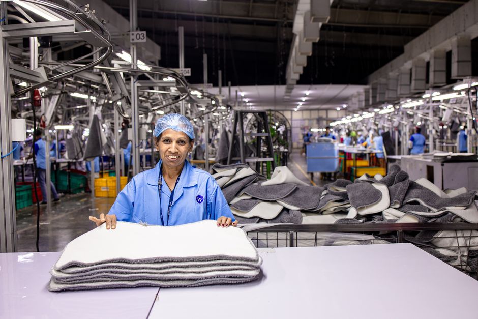 Trabalhador em fábrica têxtil manuseando equipamentos industriais