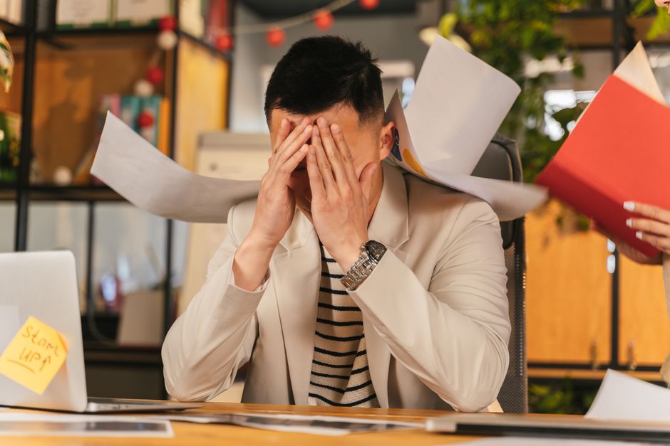 Homem estressado no ambiente de trabalho simbolizando os riscos psicossociais cobertos pela NR-1